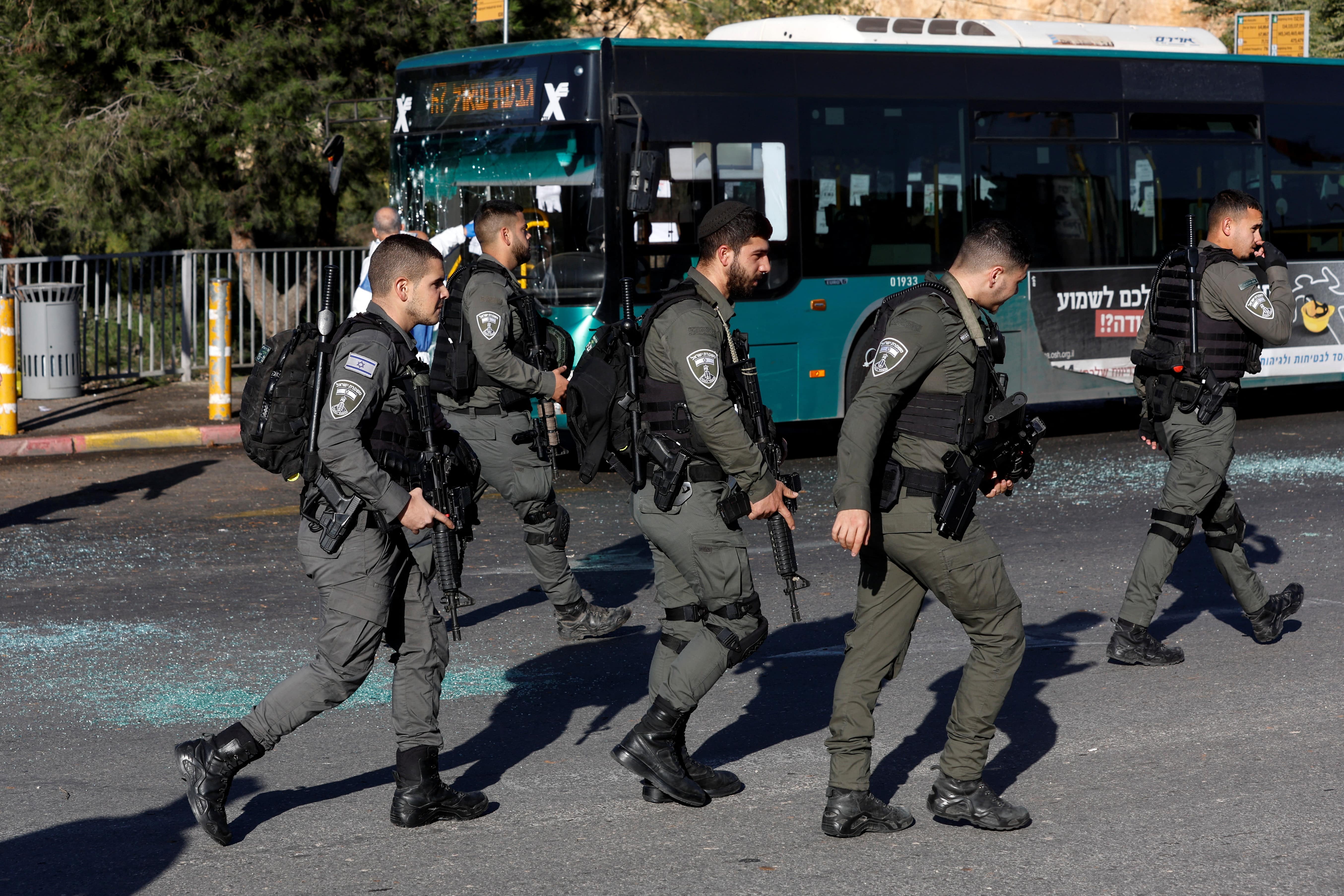 Israeli police walk past a damaged bus following an explosion at a bus stop in Jerusalem 23 November 2022 (Reuters)