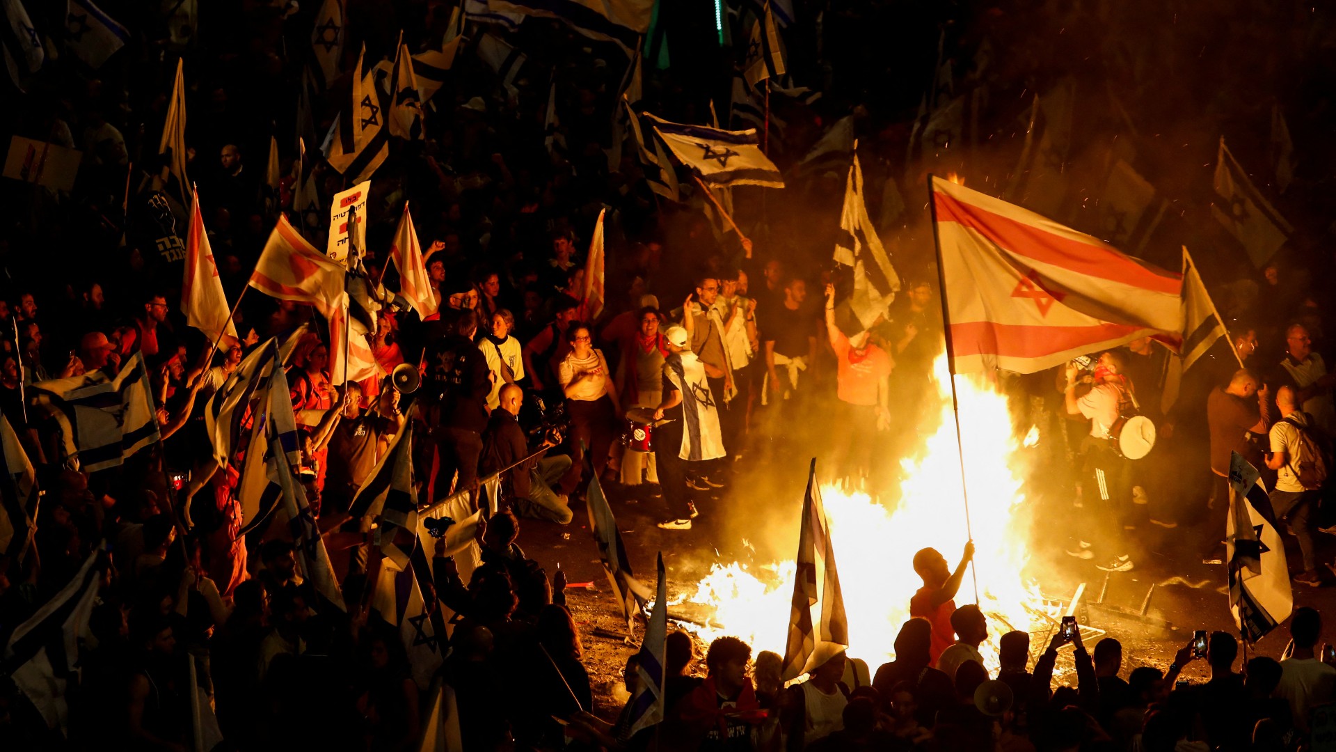 Fire burns as people attend a demonstration in Tel Aviv (Reuters)