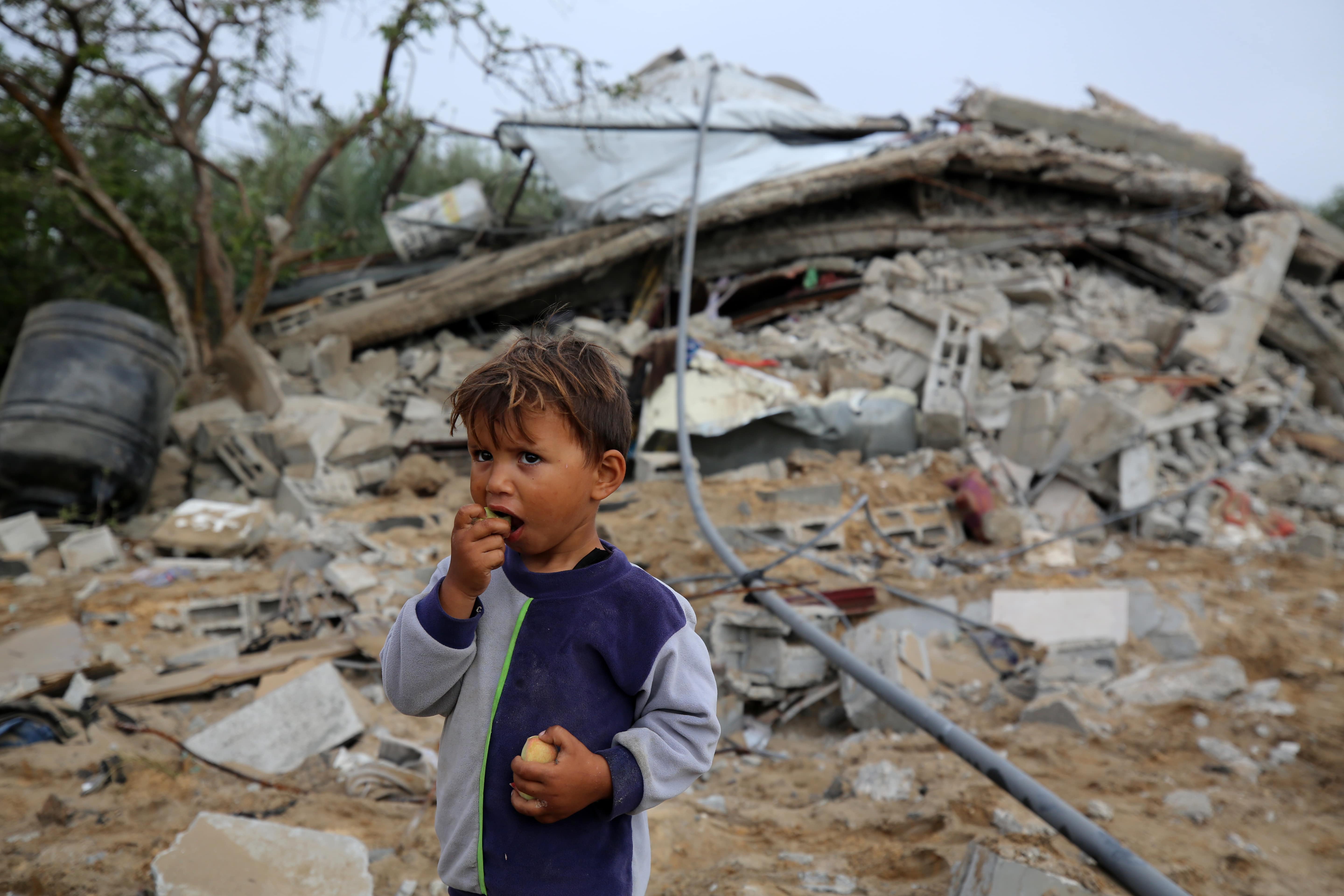 A Palestinian child stands near a damaged house following renewed Israeli air strikes in southern Gaza Strip on 11 May 2023 (Reuters)