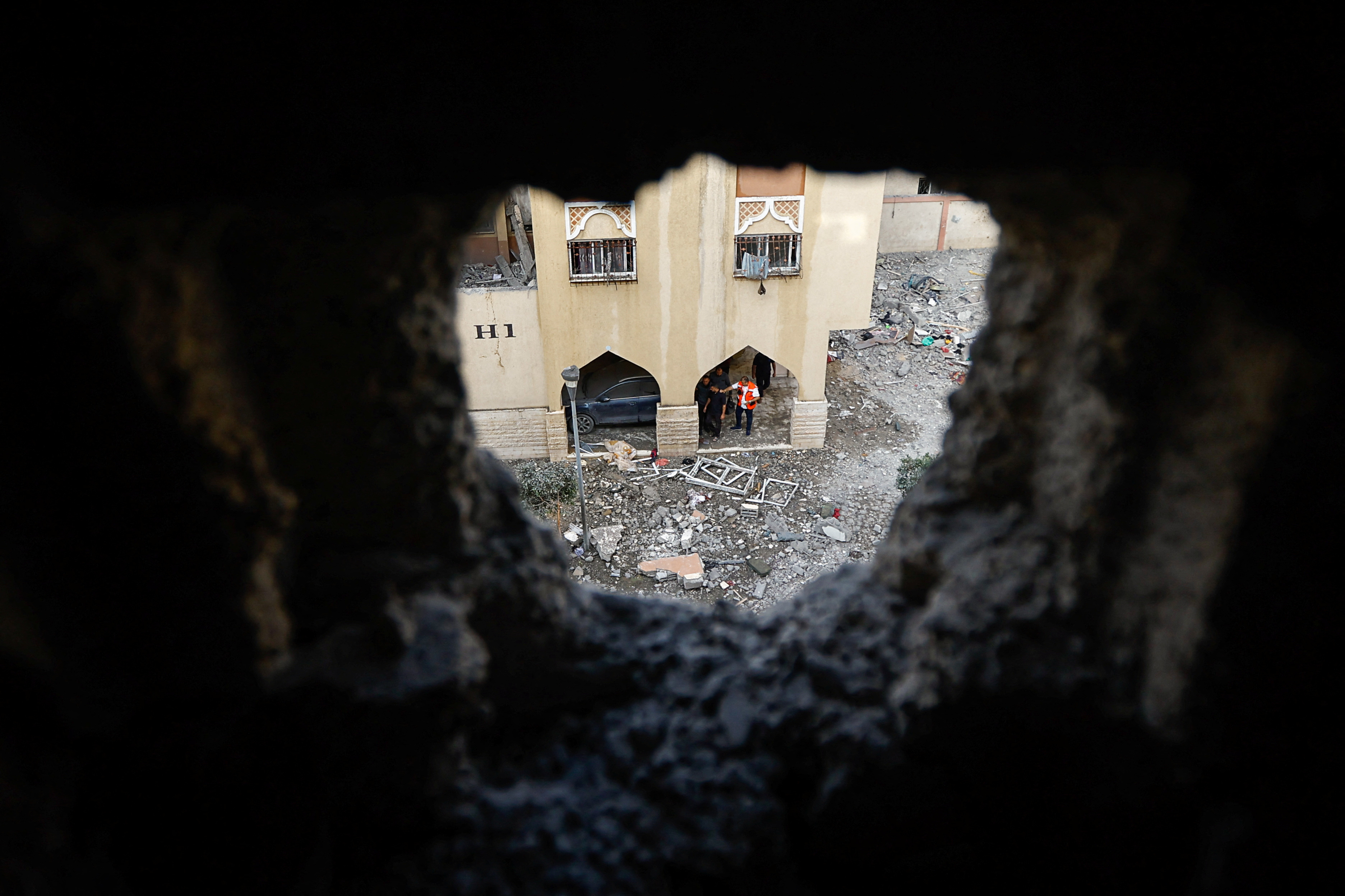 People gather near a damaged building where Islamic Jihad commander Ali Ghali was killed in an Israeli strike, in Khan Younis in the southern Gaza Strip 11 May 2023 (Reuters)