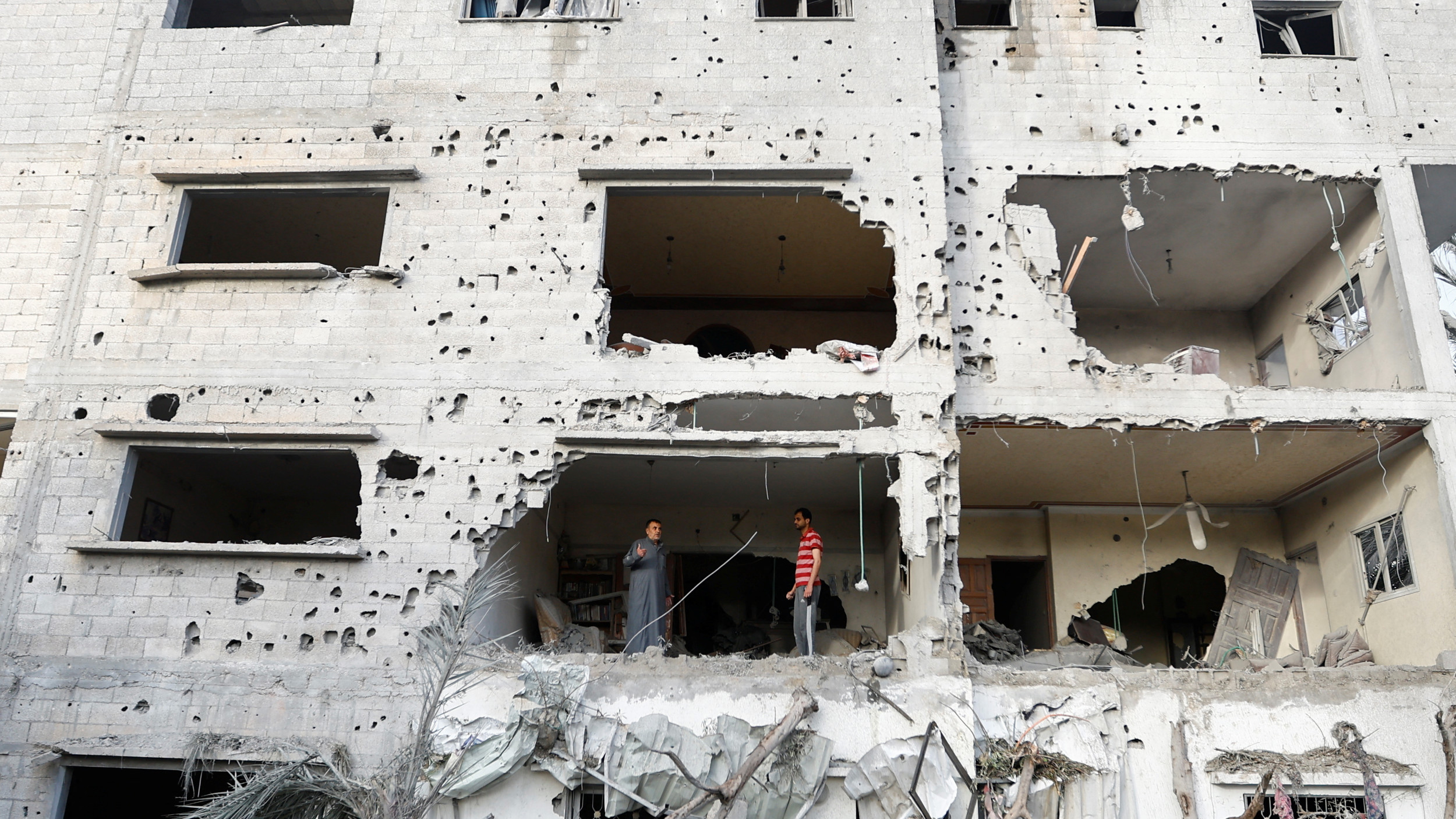 Palestinians gather at the site of an Israeli air strike in Deir al-Balah town in the central Gaza Strip, 12 May 2023 (Reuters)