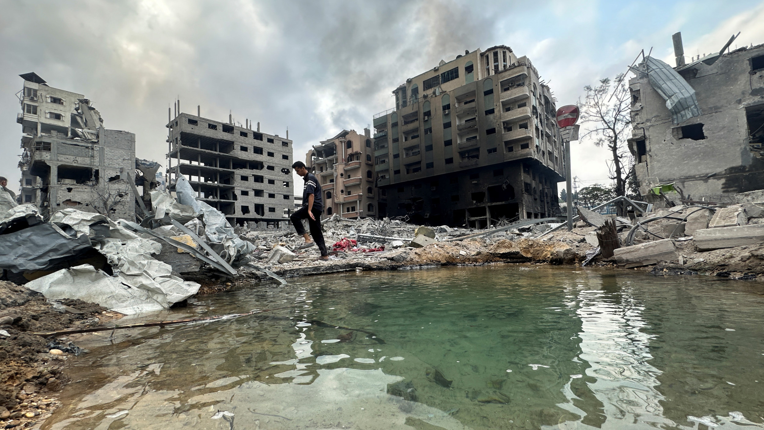 Un Palestinien marche parmi les décombres tandis que de la fumée s’élève d’un immeuble résidentiel endommagé à proximité, à la suite de frappes israéliennes, dans la ville de Gaza, le 10 octobre 2023 (Reuters)