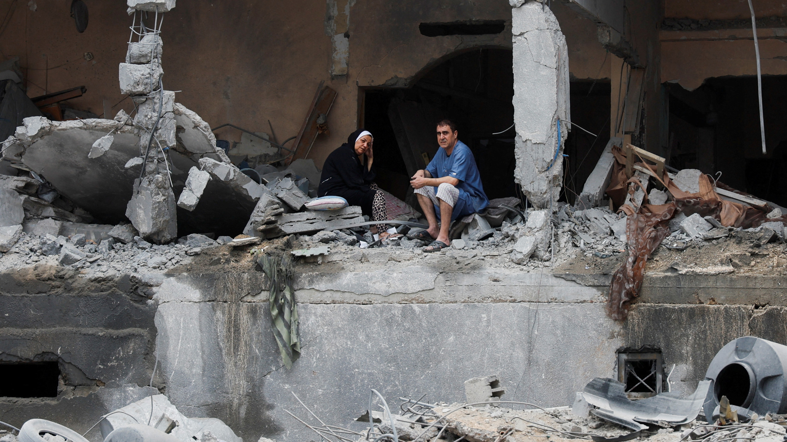 Des Palestiniens assis parmi les décombres d’un immeuble résidentiel endommagé, à la suite de frappes israéliennes, dans la ville de Gaza, le 10 octobre 2023 (Reuters)