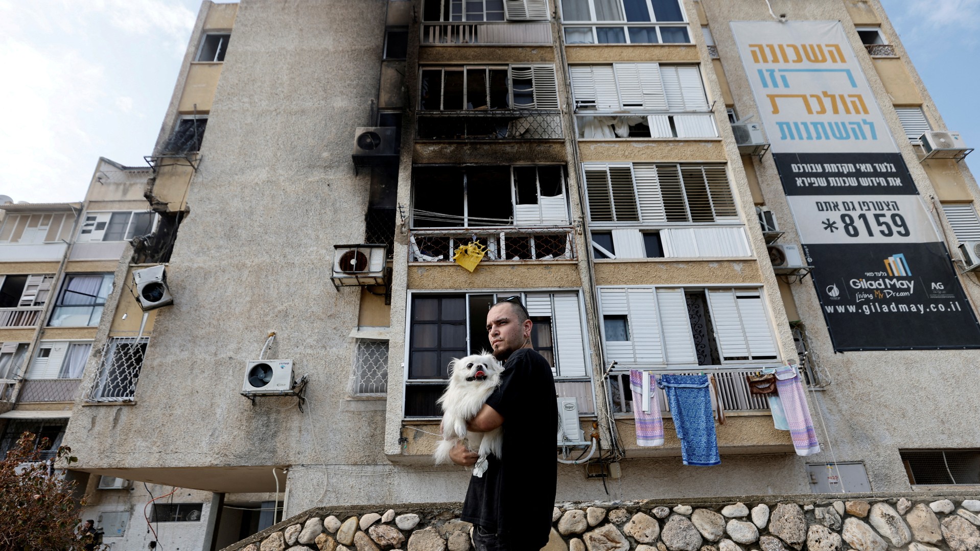 A man holds his dog after a rocket, launched from the Gaza Strip, landed in Ashkelon, 11 October (Reuters)