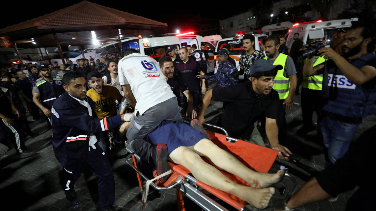 Medics carry an injured Palestinian on a stretcher after an air strike on al-Ahli hospital, 17 October 2023 (Reuters)