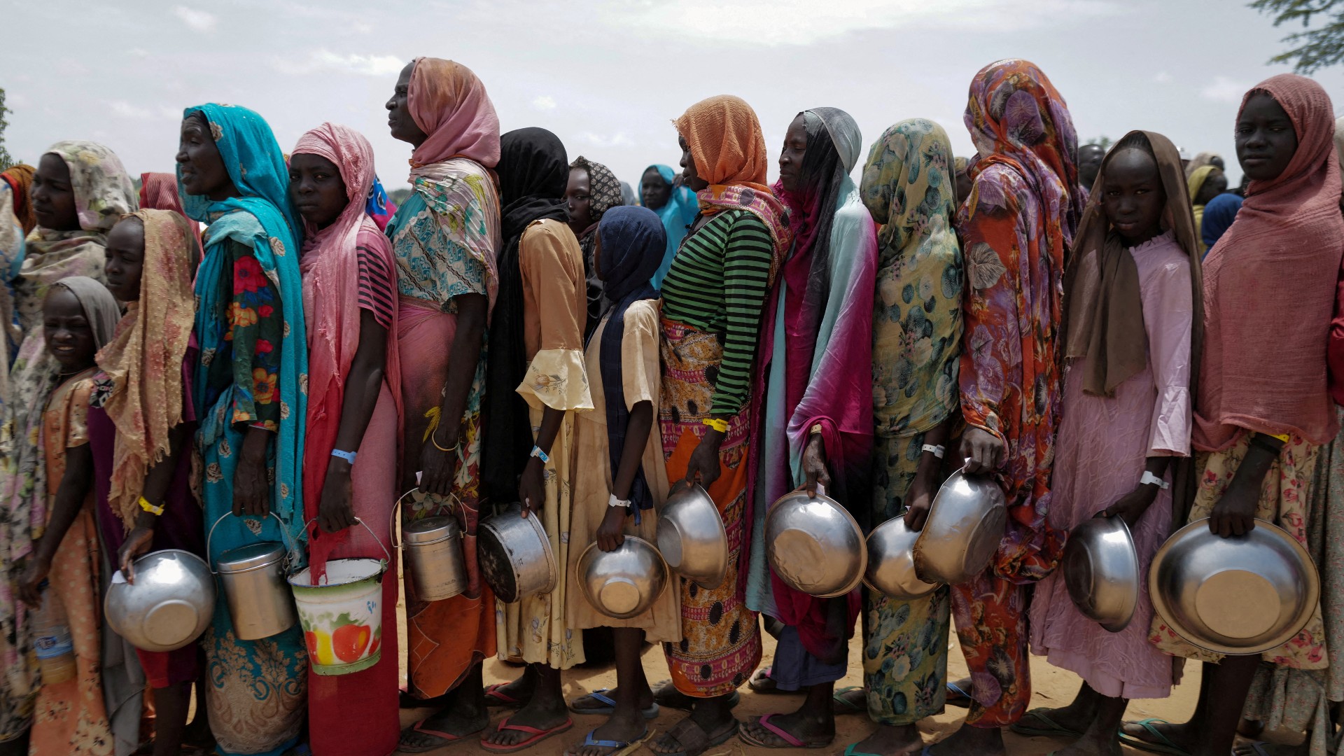 Sudanese women who fled the conflict in Sudan's Darfur region line up to receive rice portions from Red Cross volunteers in Chad (Reuters)