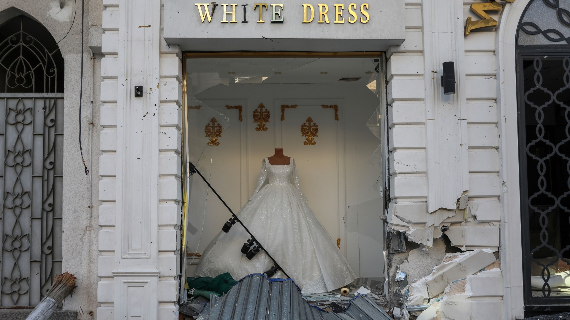 A bridal dress hangs from a shop window damaged by Israeli air strikes and shelling in Gaza City on 24 November 2023 (MEE/Mohammed al-Hajjar)