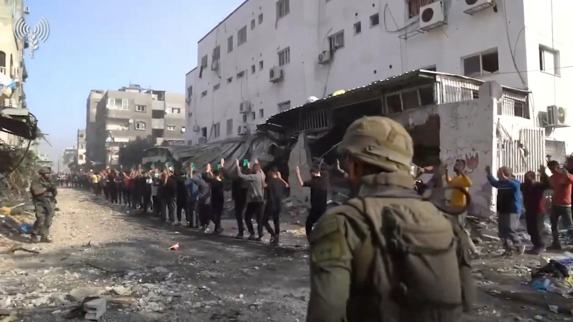 Israeli soldiers stand guard as men with raised hands are led out near Kamal Adwan hospital in the northern Gaza Strip (Screen grab from a Israeli army video released 14 December 2023 via Reuters)