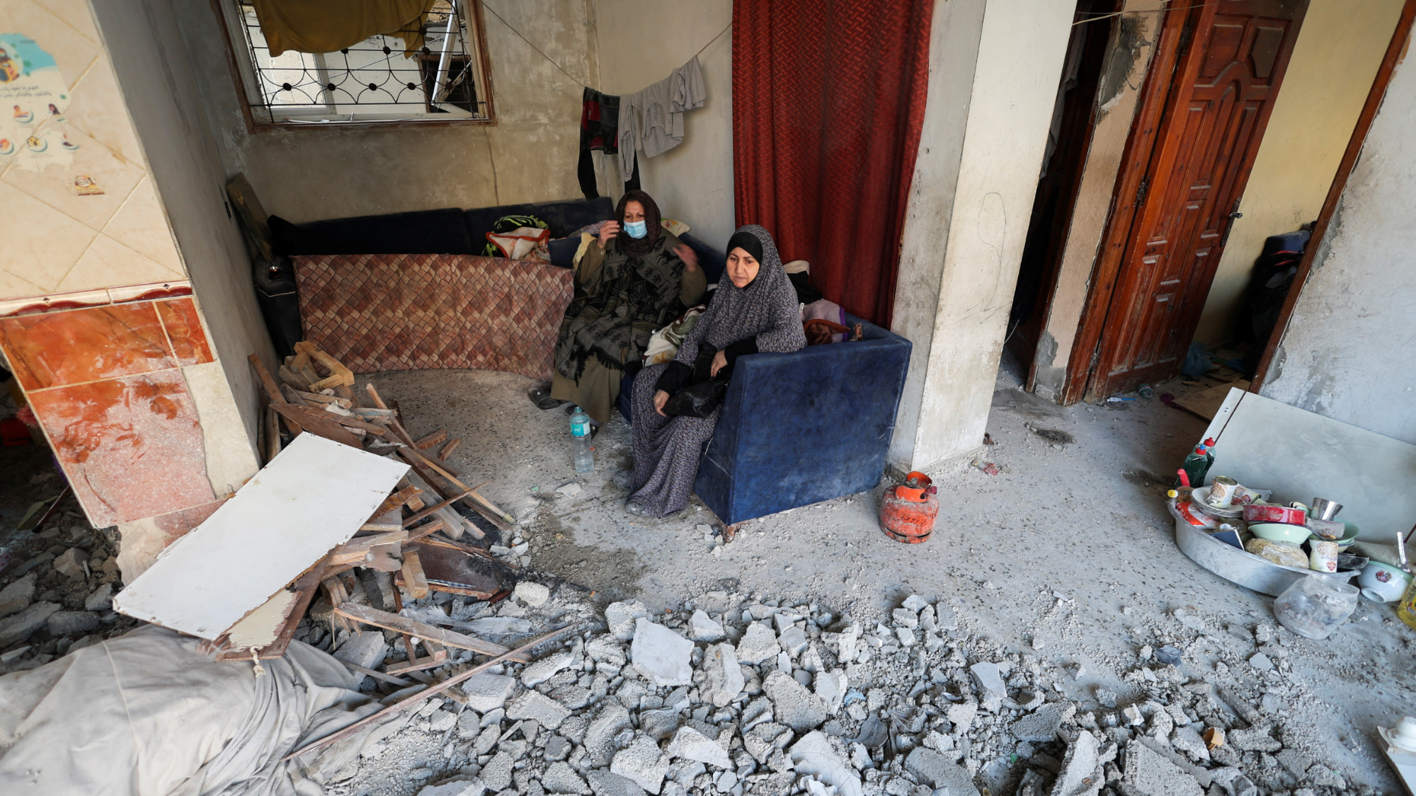 Palestinian women look on at the site of an Israeli strike on a house in Rafah on 29 December 2023 (Ibraheem Abu Mustafa/Reuters)