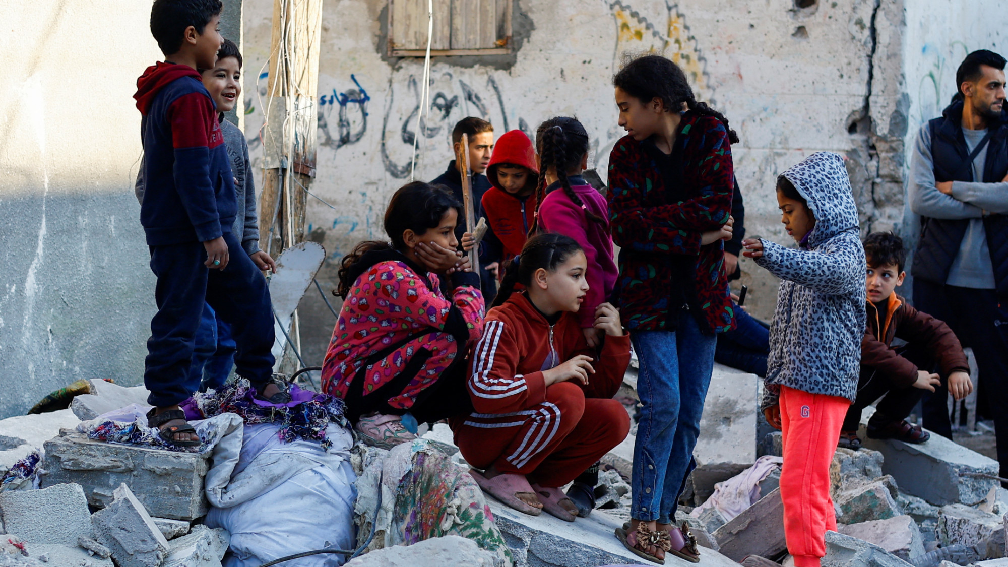 Palestinian children look on at the site of an overnight Israeli strike on a house in Rafah on 29 December 2023 (Ibraheem Abu Mustafa/Reuters)