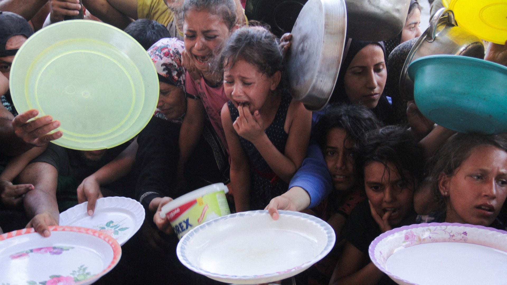 Palestinian children gather to receive food cooked by a charity kitchen, amid food scarcity, in the northern Gaza Strip, July 18, 2024. REUTERS/Mahmoud Issa