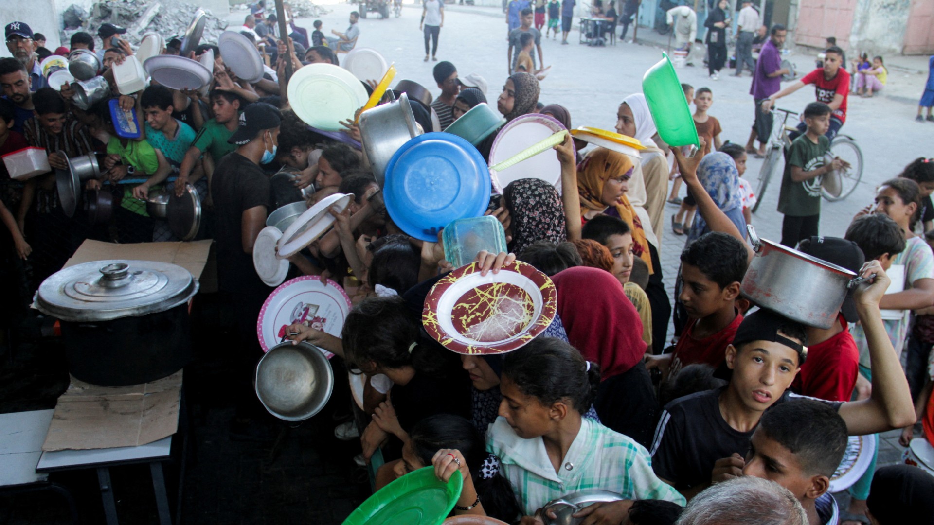 Palestinian children gather to receive food cooked by a charity kitchen, amid food scarcity in the northern Gaza Strip, July 18, 2024. REUTERS/Mahmoud Issa