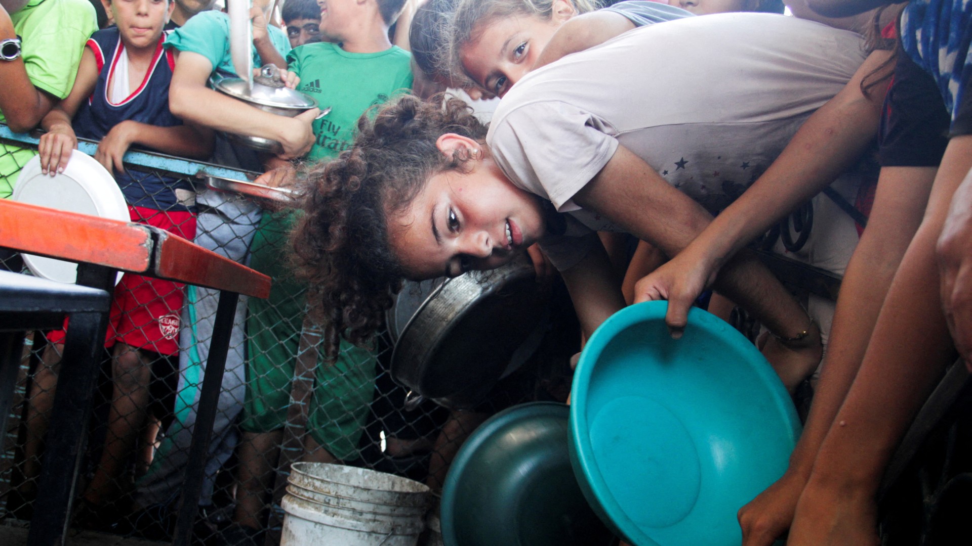 Palestinian children gather to receive food cooked by a charity kitchen, amid food scarcity in the northern Gaza Strip, July 18, 2024. REUTERS/Mahmoud Issa