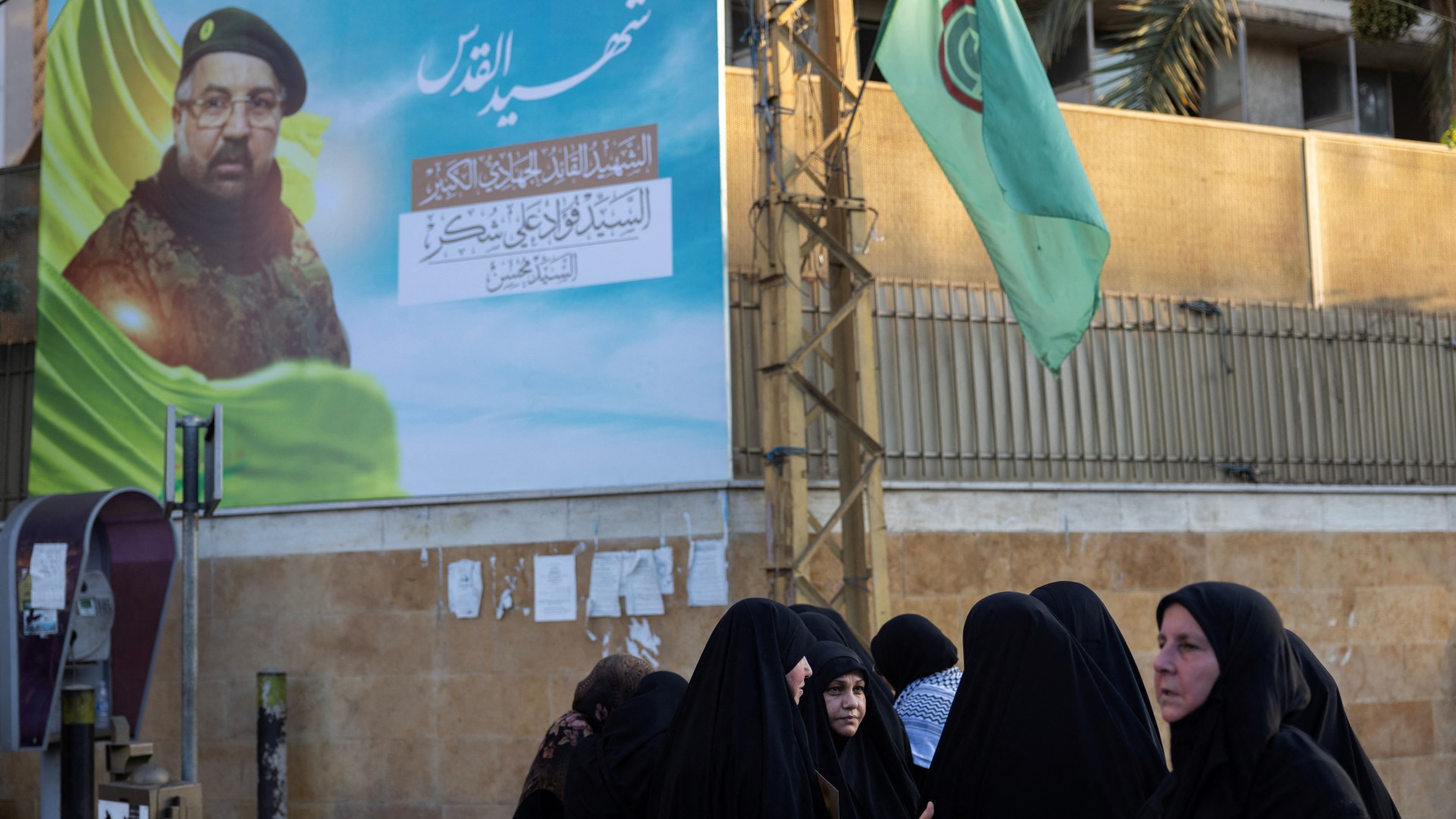 Women stand next to a poster depicting Hezbollah senior commander Fuad Shukr, who was killed in an Israeli strike, in Beirut's southern suburbs, Lebanon 1 August, 2024 (Alkis Konstantinidis/Reuters)