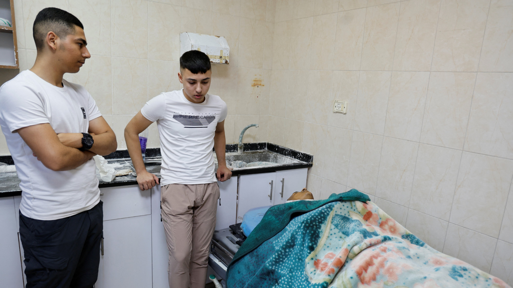 People stand next to the body of a Palestinian, who was killed during an Israeli raid in al-Far'a camp, at a hospital in Tubas, in the occupied West Bank 28 August 2024 (Reuters/Raneen Sawafta) 