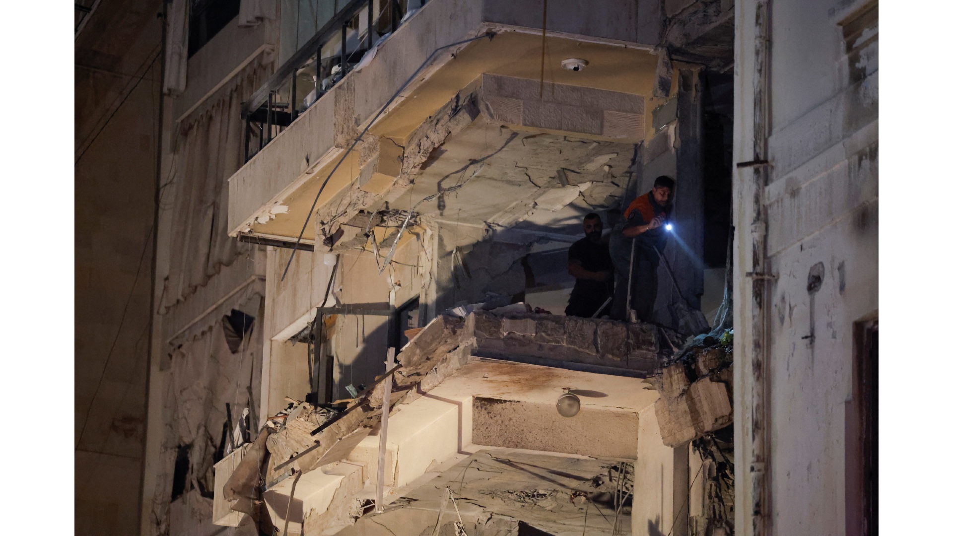 A person uses light to inspect inside a damaged building at the site of an Israeli air strike in Ras Al- Nabaa, in Beirut, Lebanon, October 10, 2024. 