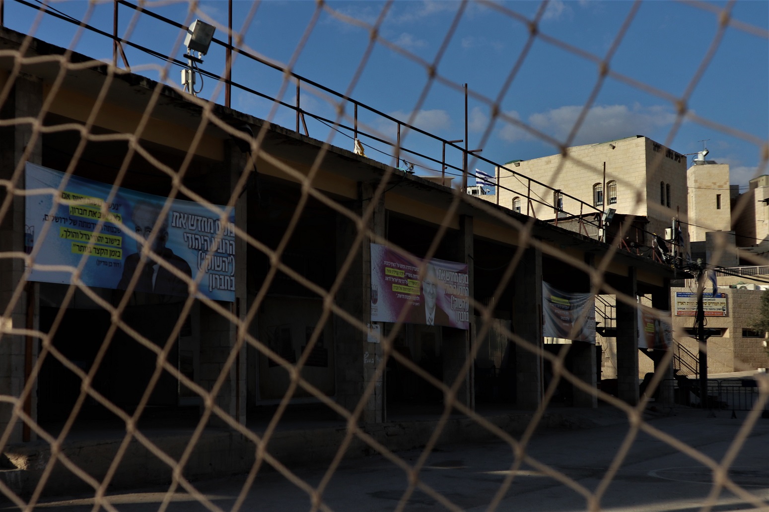Bannières avec des figures de la politique israélienne ou religieuses placardées sur les bâtiments de l’ancien marché aux légumes. On peut y lire : « Nous reconstruisons le quartier juif, ‘’le souk’’, à Hébron (MEE/Marie Niggli)