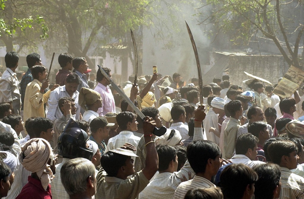 A Hindu mob waves swords at an opposing Muslim crowd during street battles in Ahmedabad on 1 March 2002 (Sebastian D'Souza/AFP)