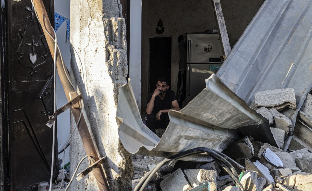 A Palestinian man sits amid the rubble of a building following Israeli air strikes in Rafah in the southern Gaza Strip, on 7 August 2022 (AFP)