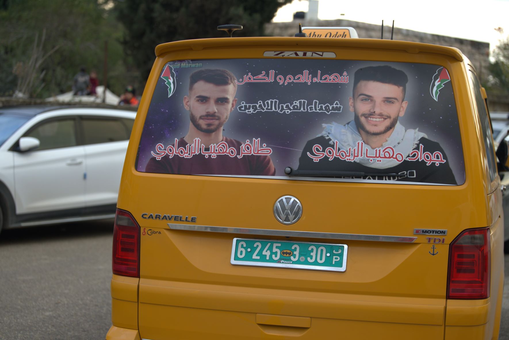 A Palestinian taxi featuring a poster of the two martyred brothers, Jawad and Thafer Rimawi, at their funeral (MEE/Akram al-Waara)