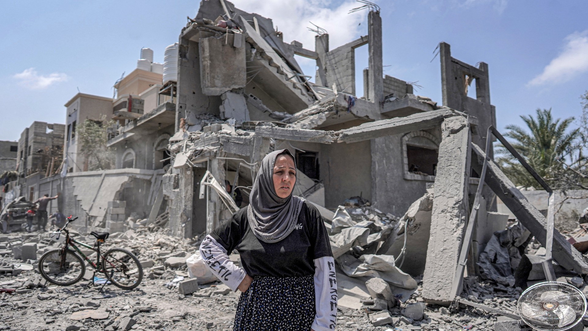 A Palestinian woman stands amidst rubble before a collapsed building in the eastern side of the Maghazi camp for Palestinian refugees in the central Gaza Strip on 15 April, 2024  (AFP)