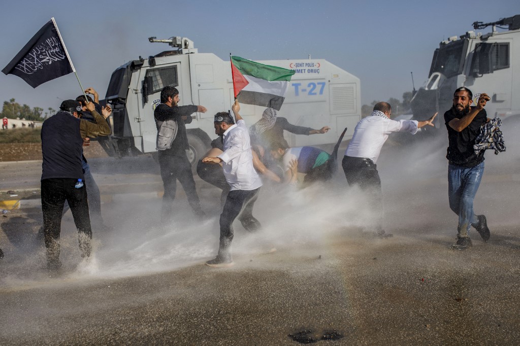 Protestors hold a Palestinian flag as Turkish anti-riot police use water cannon to disperse them during a Pro-Palestinian demonstration