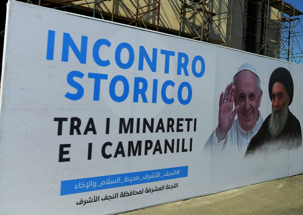 A billboard marks the historic meeting between the Pope and Sistani, with a slogan in Italian reading: ‘The historic meeting between minarets and bells’ (Vatican Media/AFP)