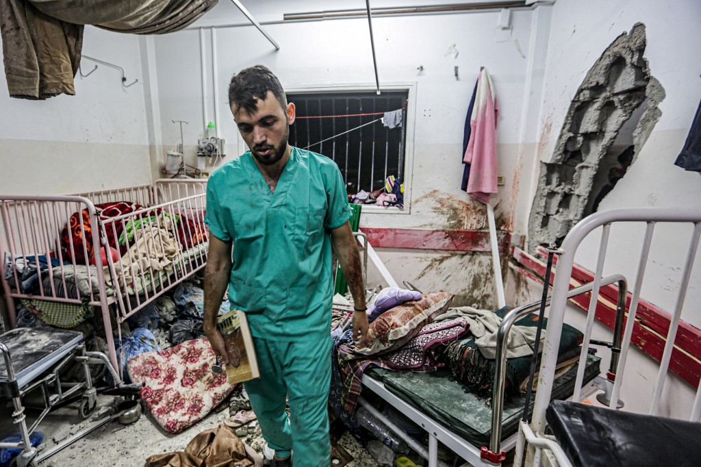 A medic inspects the damage in a room following Israeli bombardment of Nasser hospital in Khan Younis, southern Gaza Strip, on 17 December 2023 (AFP)