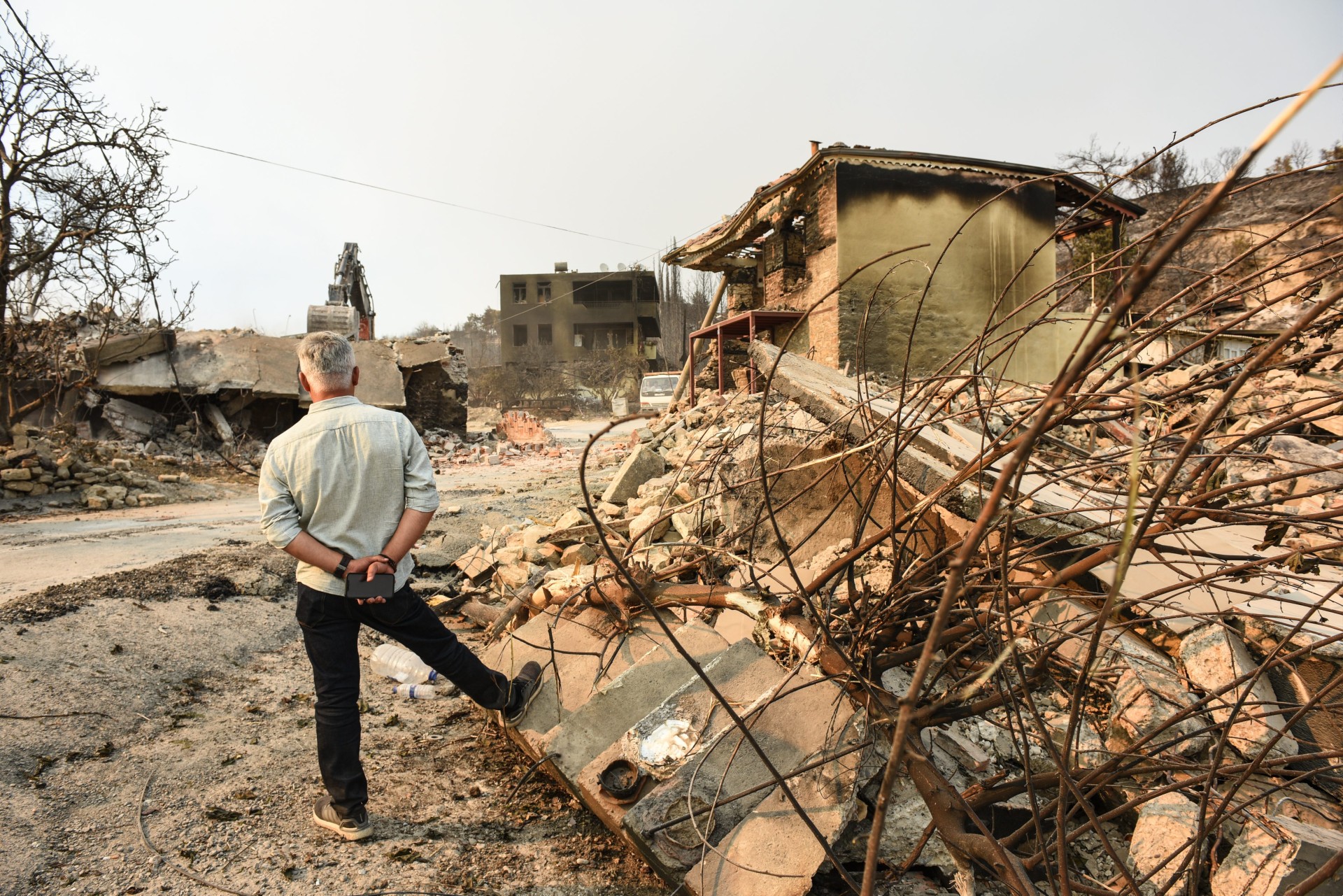 A man looks at his burned house while standing in front of the rubble of another house (MEE/Yusuf Selman İnanc)