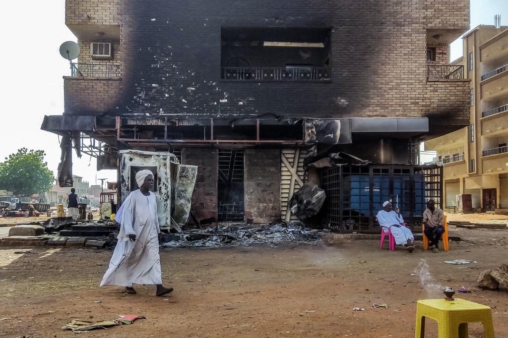 A man walks past a burned-out bank branch in southern Khartoum, 24 May 2023 (AFP)