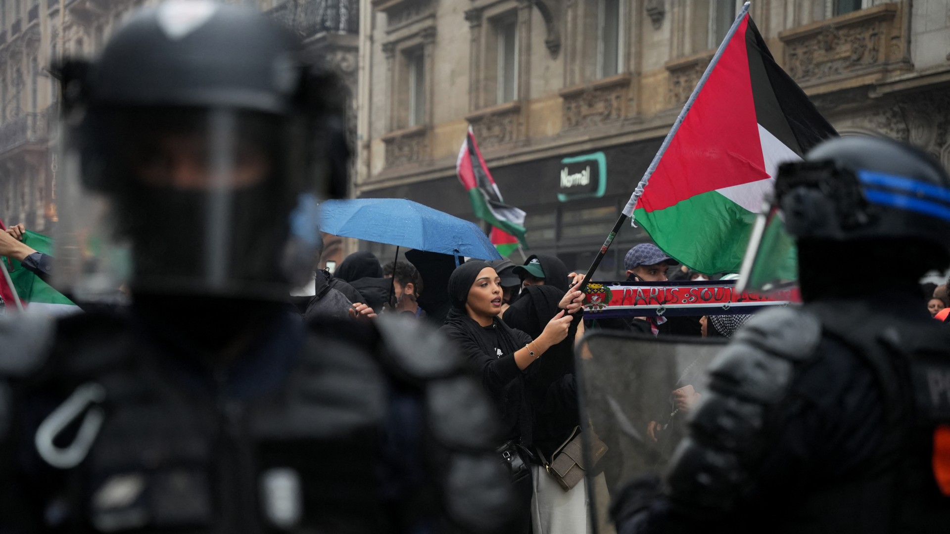 A protester waves a Palestinian flag facing French riot-Police officers during a rally in central Paris on May 29, 2024