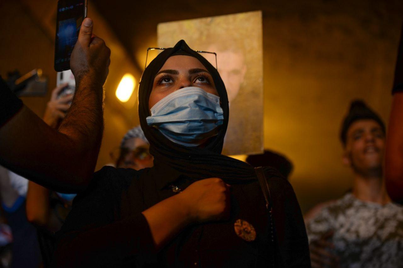 A women protester wearing a mask and giving the respect of the national anthem a day before the anniversary of Iraq's 2019 protests.