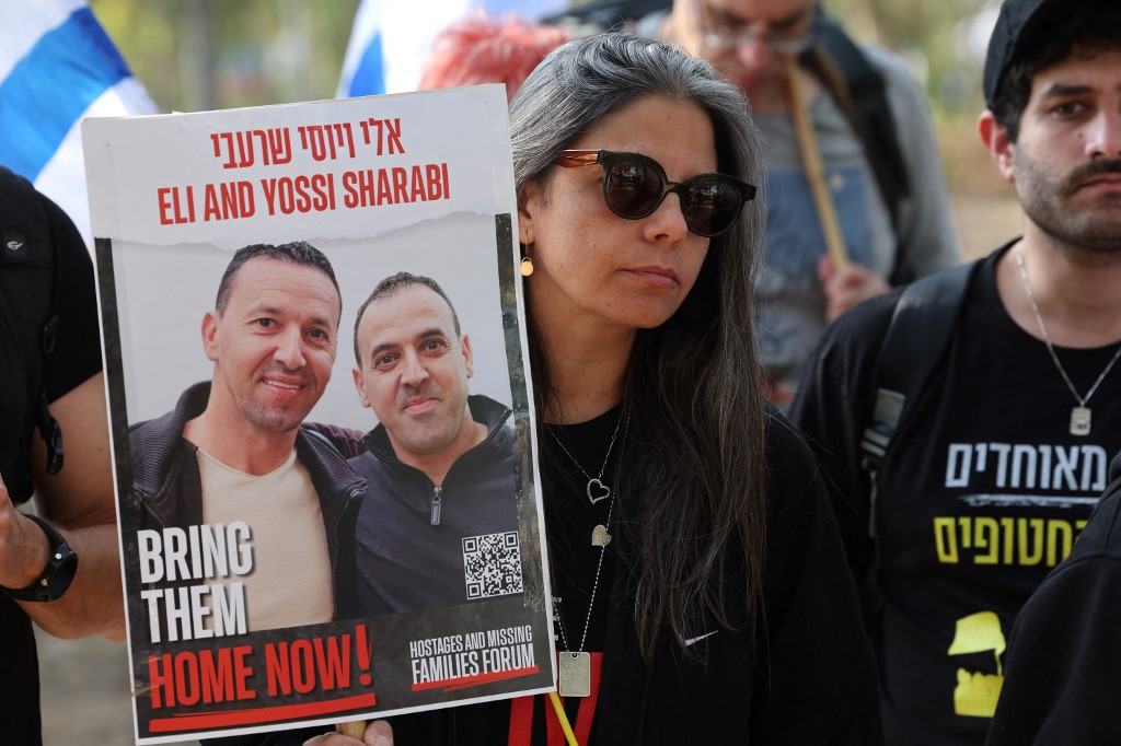 A woman holds a portrait of hostages Eli and Yossi Sharabi (Jack Guez / AFP)