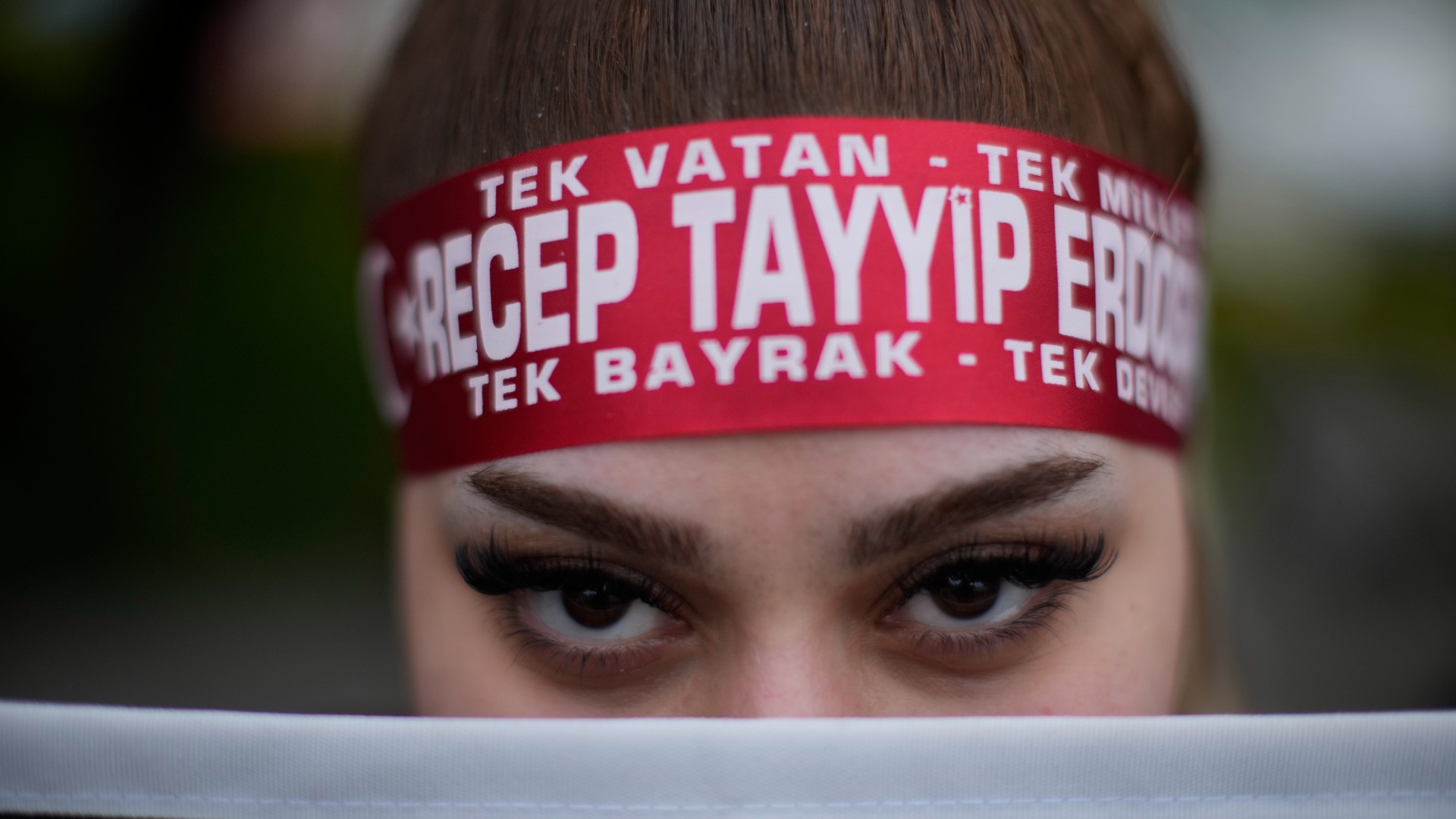 A supporter of President Recep Tayyip Erdogan stands outside the headquarters of AKP in Istanbul (AP)