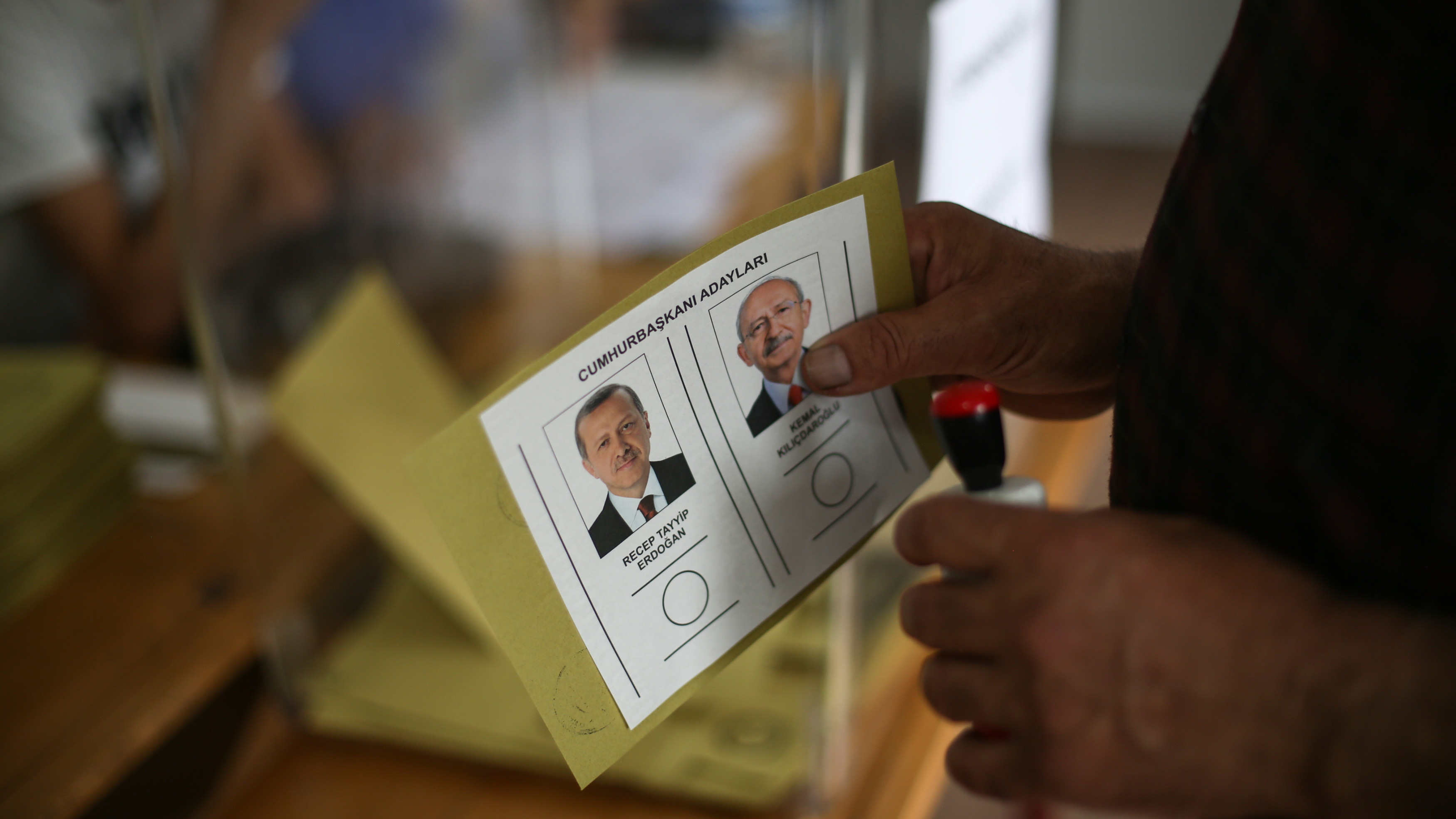 A man holds a ballot with the names and images of Recep Tayyip Erdogan and Kemal Kilicdaroglu before voting in Malatya on 28 May 2023 (AP)