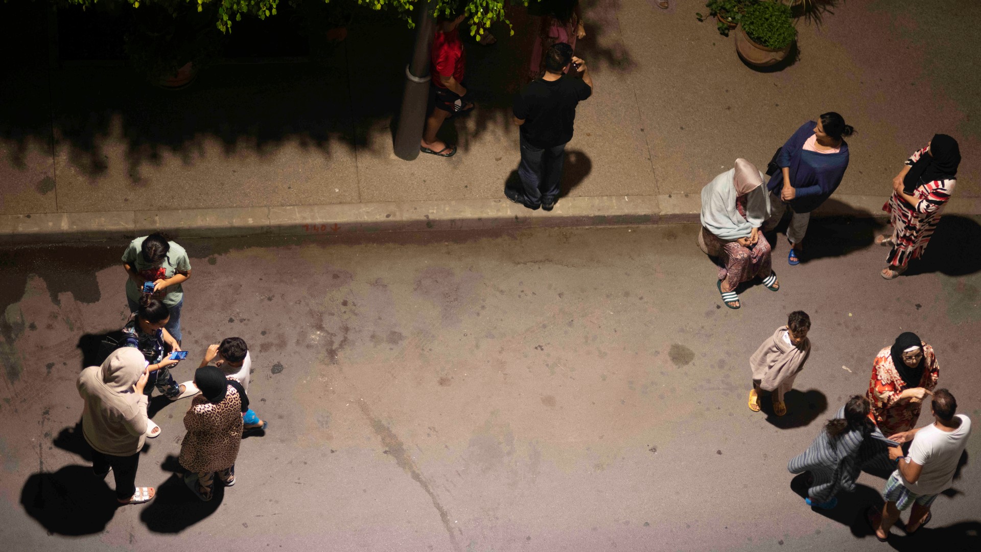 People take shelter and check for news on their mobile phones after an earthquake in Rabat (AP)