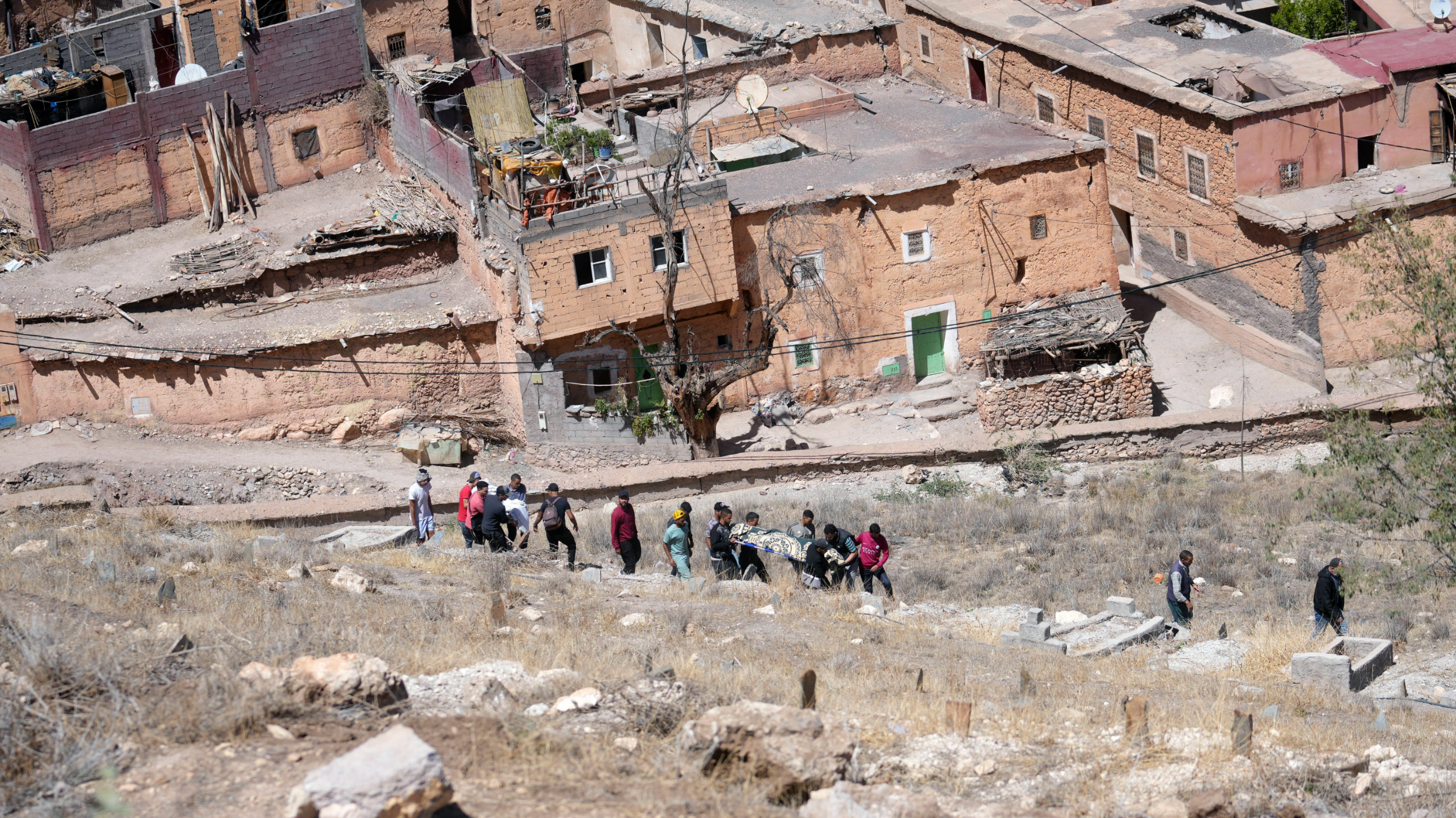 People prepare to burry a man who was killed by the earthquake in Moulay Brahim village near Marrakech on 9 September 2023 (AP)