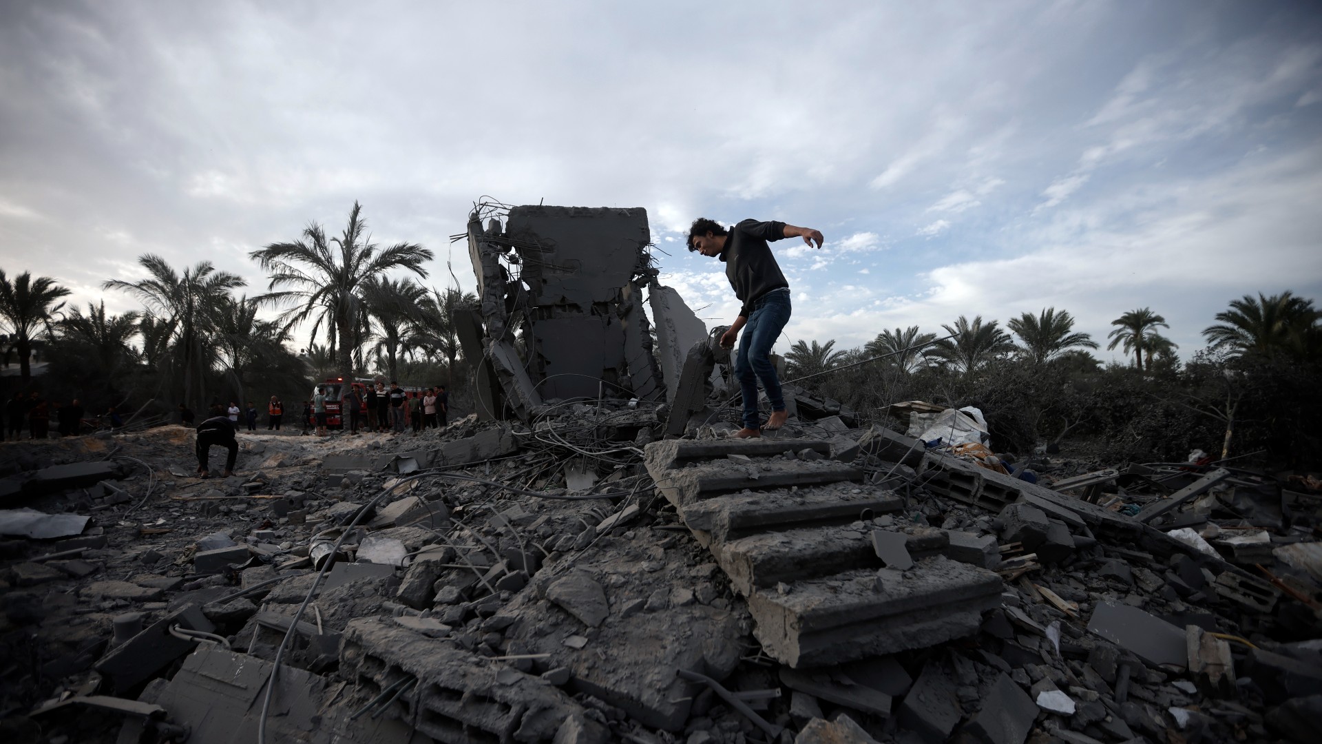 Palestinians inspect the damage of a destroyed house following Israeli air strikes in the town of Khan Younis, southern Gaza Strip, 22 November (AP)