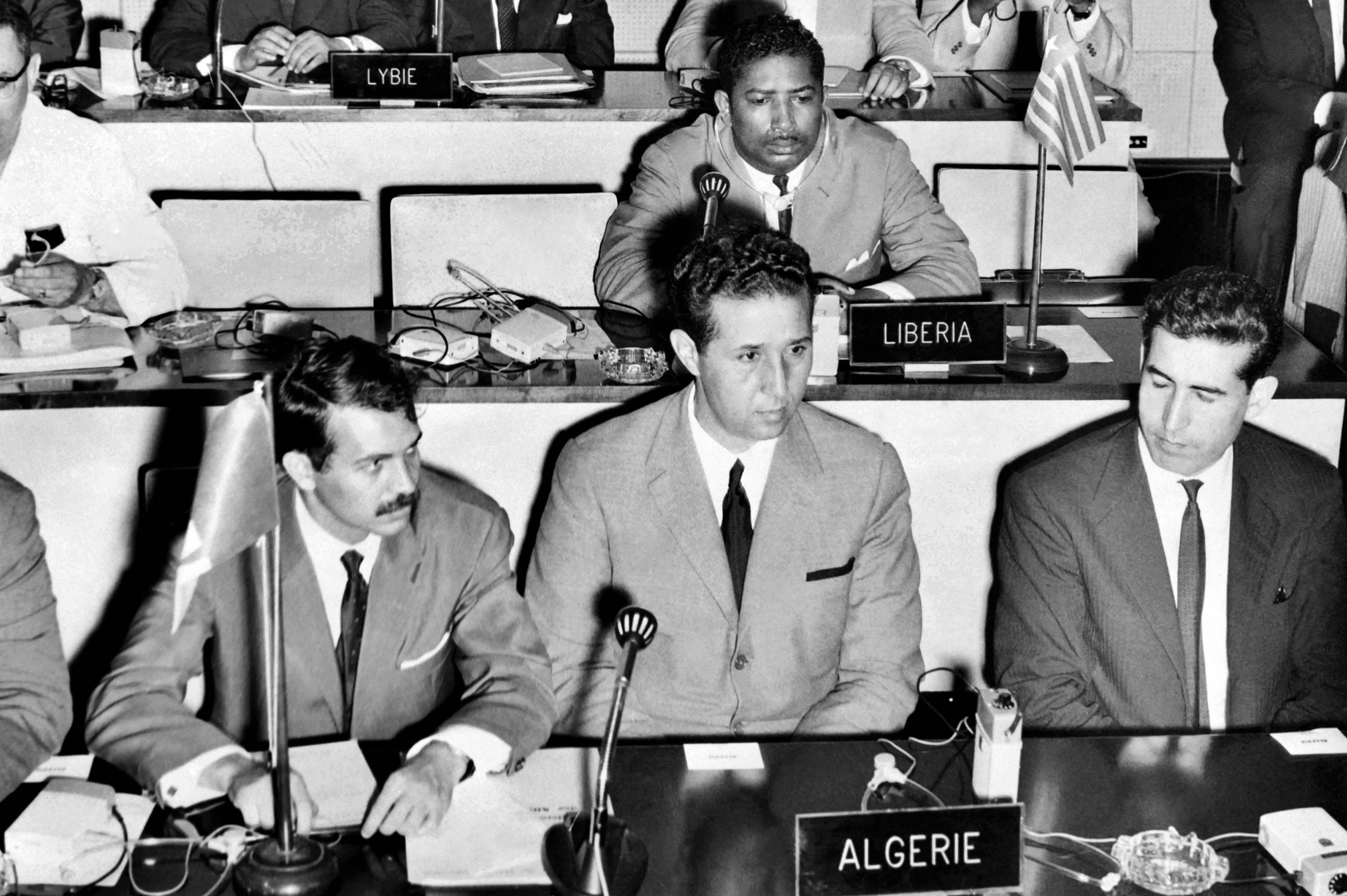 Bouteflika, left, then the minister of youth, sport and tourism, sits next to President Ahmed Ben Bella during a meeting of the Organisation of African Unity in Senegal in August 1963 (AFP)