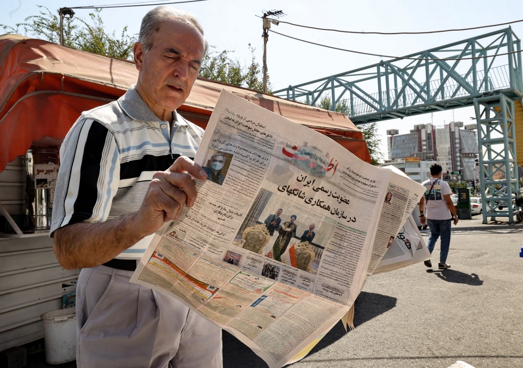 A man reads a copy of the Etalaat newspaper bearing the headline 'Iran is a new member of the Shanghai Cooperation Organisation', in the capital Tehran, on 18 September 2021 (AFP)