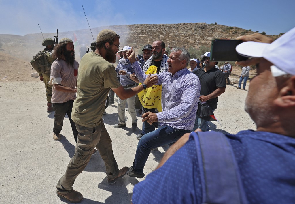 An Israeli settler confronts a Palestinian protester during a demonstration against settlement expansion, in al-Mughayer, east of Ramallah, in the occupied West Bank, 29 July 2022 (AFP)