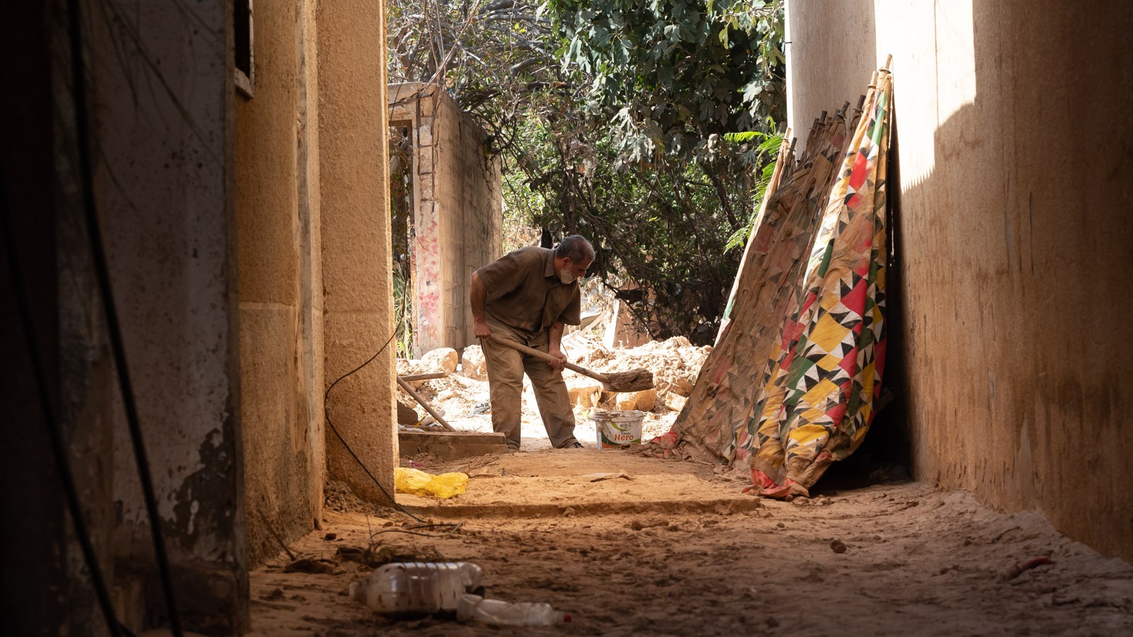 Atiya cleans the mud outside his home in Derna, Libya (MEE/Taha Jawashi)