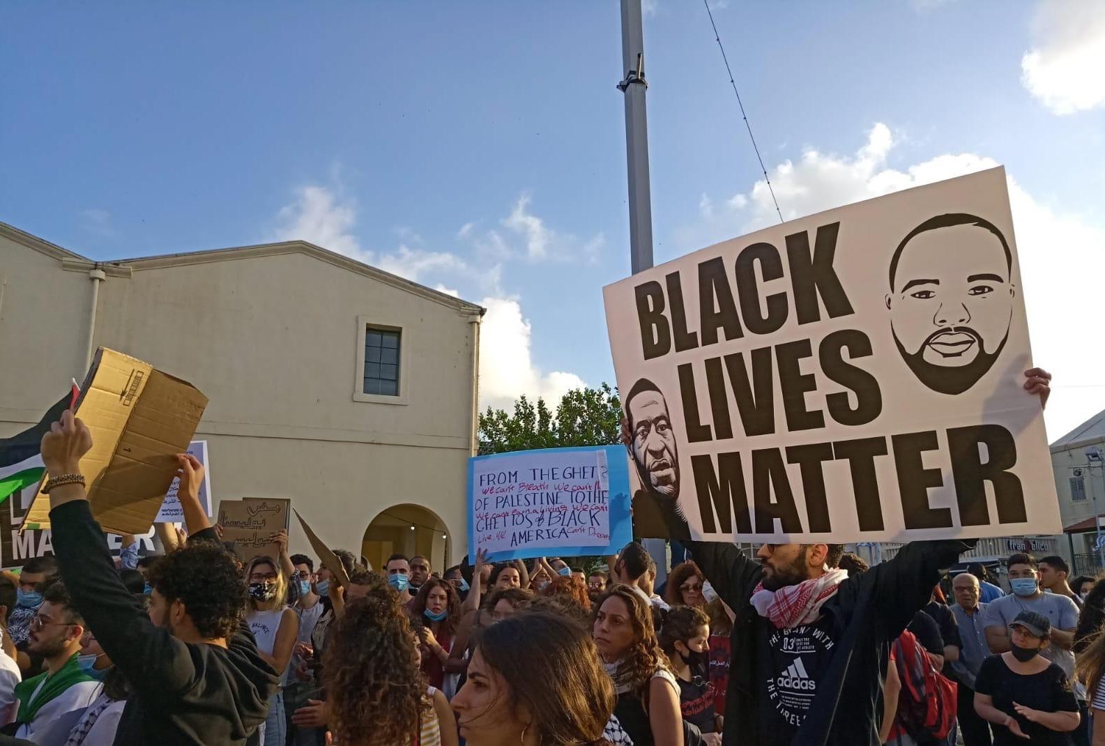 A demonstrator holds up a Black Lives matter protester in Haifa on 2 June (MEE)