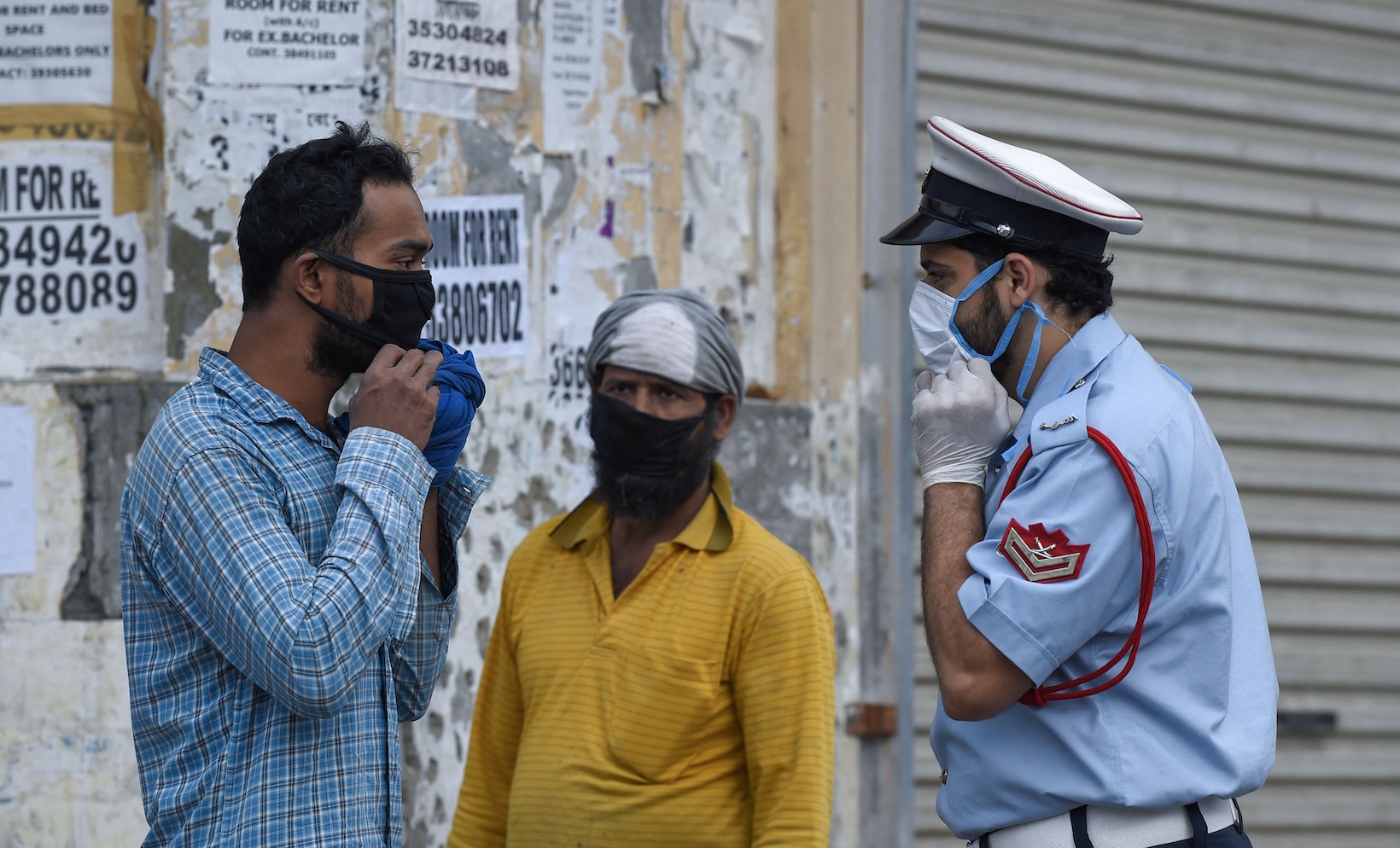 Un policier bahreïni demande à un travailleur étranger de porter son masque de protection au milieu de la pandémie de COVID-19, dans la capitale Manama, le 13 avril 2020 (AFP/Mazen Mahdi)