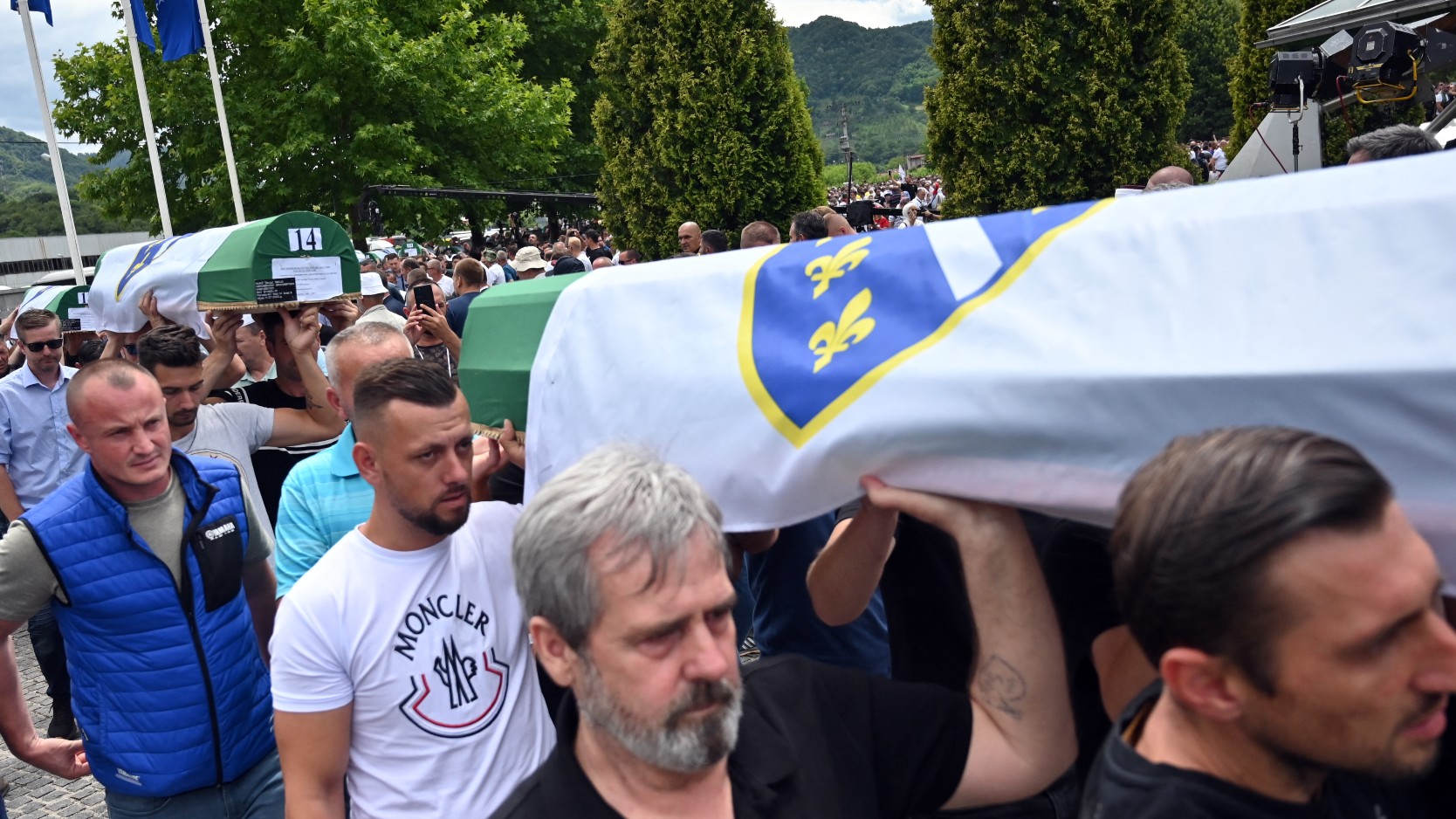 Bosnian Muslim men carry caskets containing remains of the victims of the 1995 Srebrenica massacre, at the memorial cemetery in the village of Potocari, near eastern Bosnian town of Srebrenica, on July 11, 2022