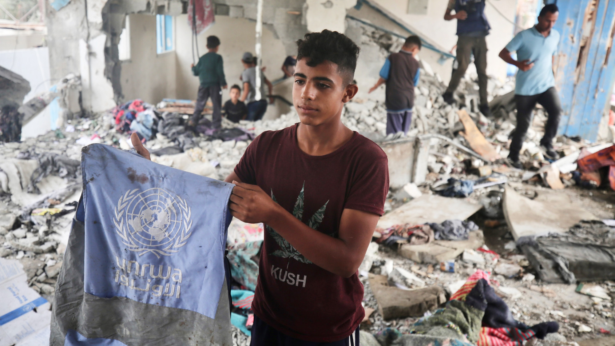 A Palestinian boy hold a blood-stained UN vest in the bombed school (MEE/Mohammed al-Hajjar)