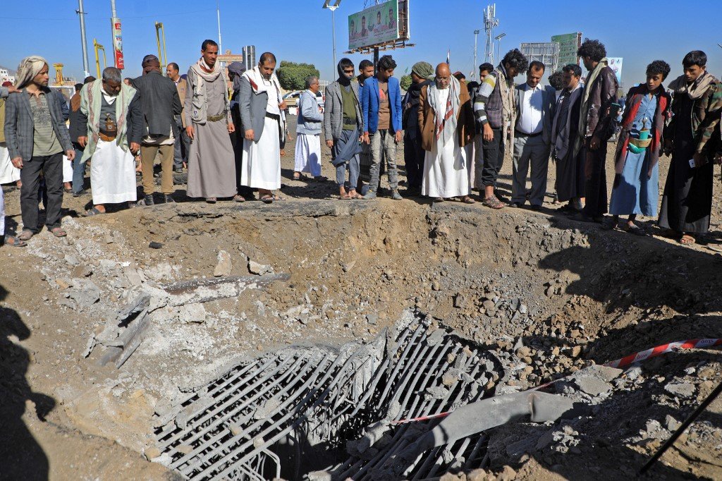 Des Yéménites inspectent un cratère à la suite d’une frappe aérienne imputée à la coalition saoudienne visant une route sur la place al-Sabeen, dans la capitale Sanaa contrôlée par les Houthis, le 23 décembre 2021 (AFP)