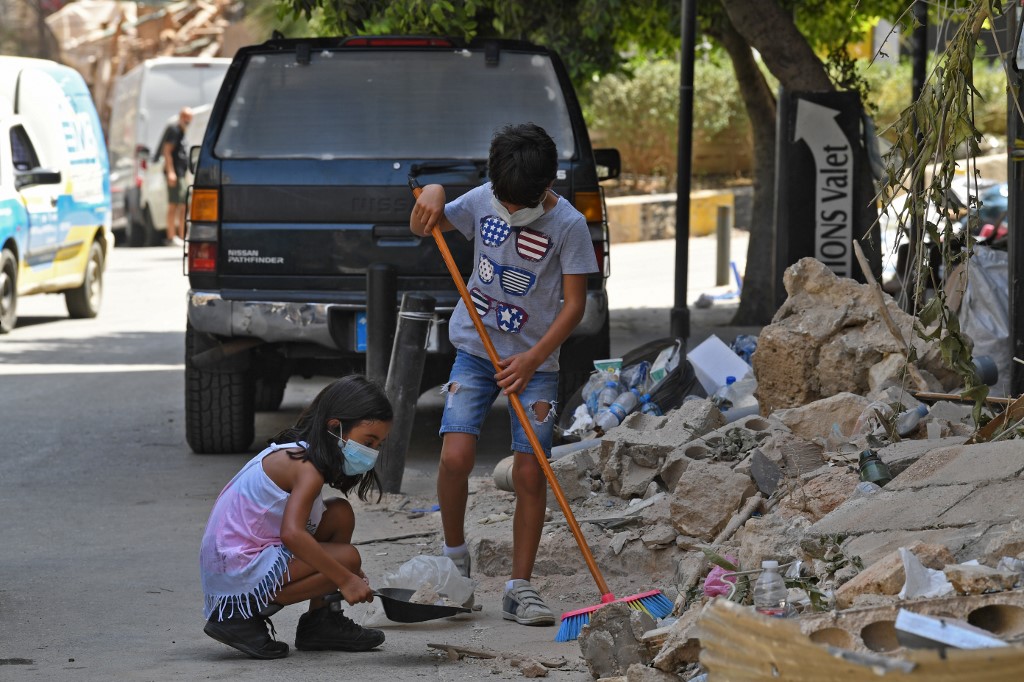 Des enfants libanais nettoient les débris de l’explosion, dans le quartier de Gemmayzeh à Beyrouth, le 8 août 2020 (AFP)