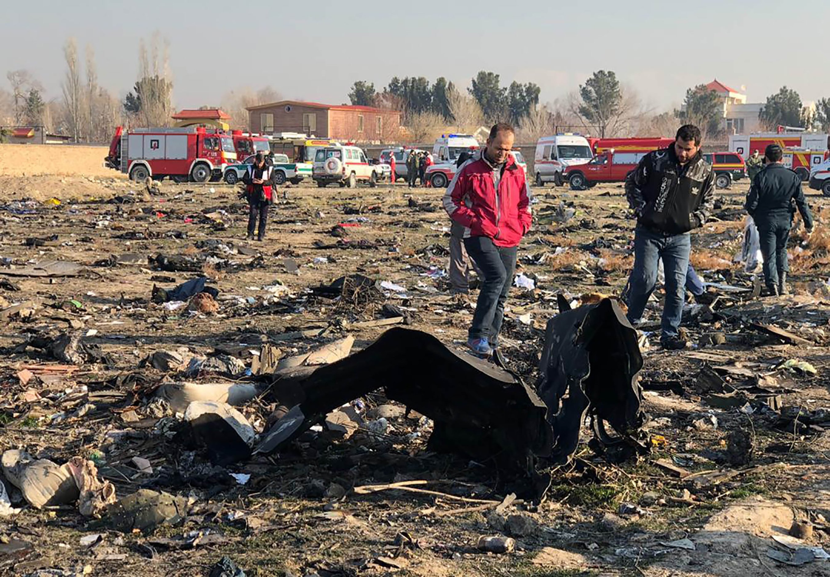 Des gens marchent près de l’épave de l’avion ukrainien qui s’est écrasé près de l’aéroport Imam Khomeini de Téhéran tôt le matin du 8 janvier 2020 (AFP)