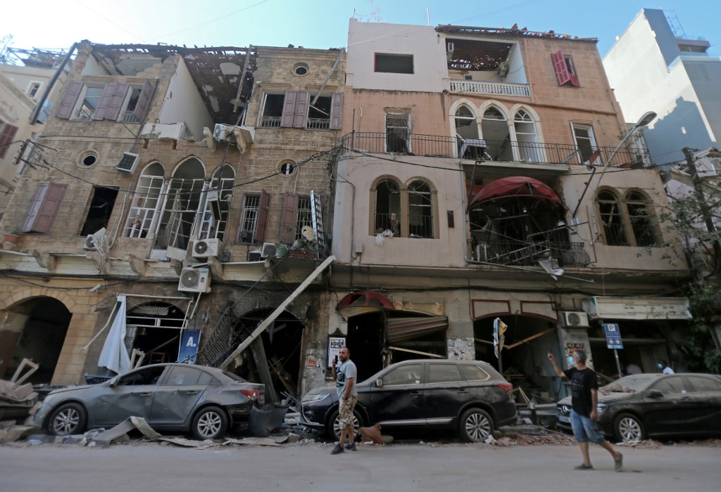 Des piétons passent devant des bâtiments historiques endommagés dans le quartier beyrouthin de Gemmayzeh, fortement endommagé par l’explosion, le 5 août 2020 (AFP)